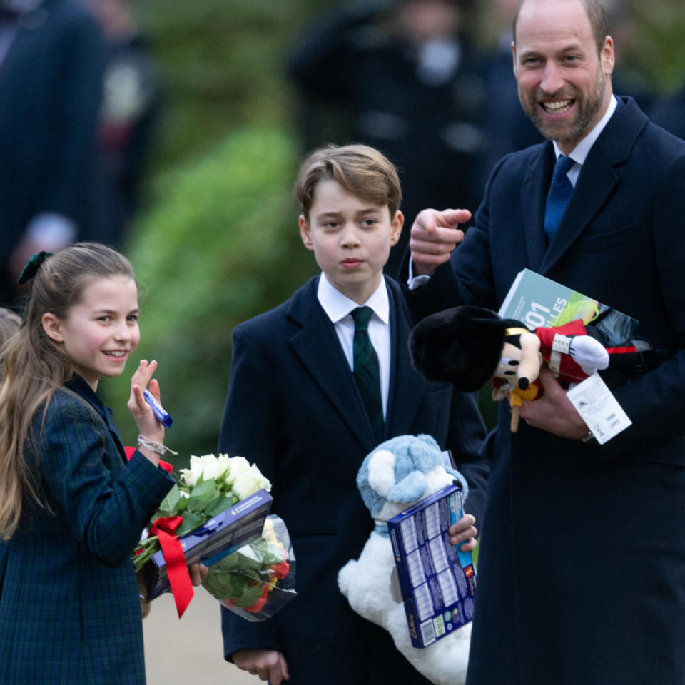 Princess Charlotte, Prince George, and Prince Louis carry gifts from royal fans at Sandringham as they stand with father Prince William on Christmas Day.