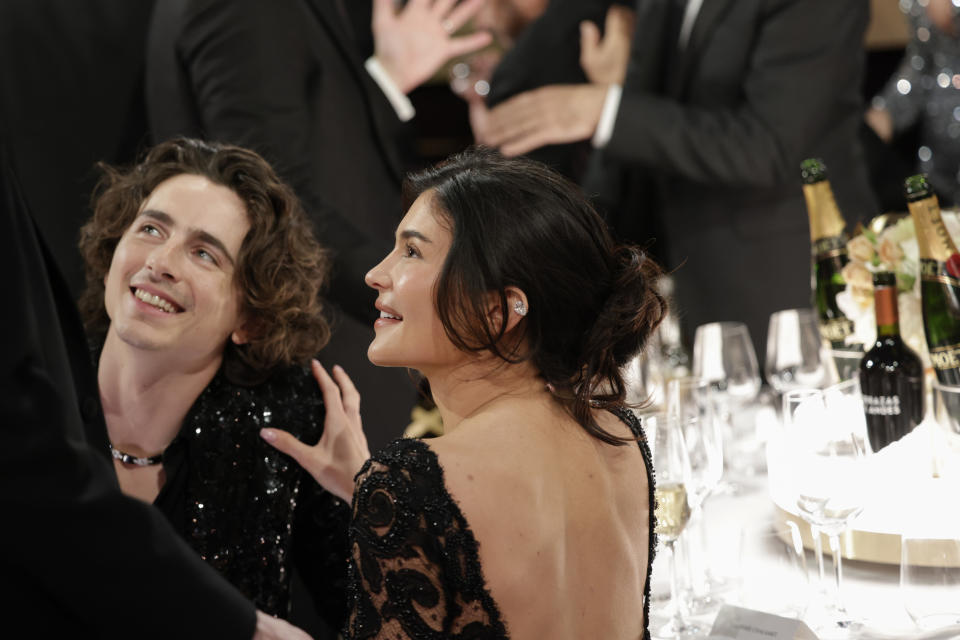 Timothée Chalamet and Kylie Jenner seated at a table, smiling and interacting