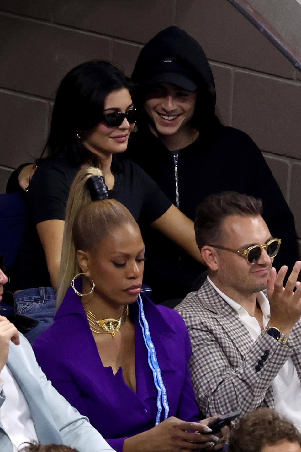 Kylie Jenner and Timothée Chalamet in casual outfits sitting close, watching an event