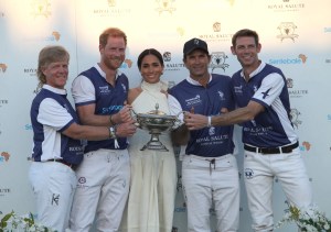 The Duchess of Sussex presents the trophy to her husband, the Duke of Sussex after his team the Royal Salute Sentebale Team defeated the Grand Champions Team