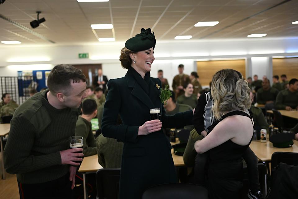Kate Middleton holding a glass of beer and laughing talking to a mom and child at the Irish Guards mess hall on March 17, 2025