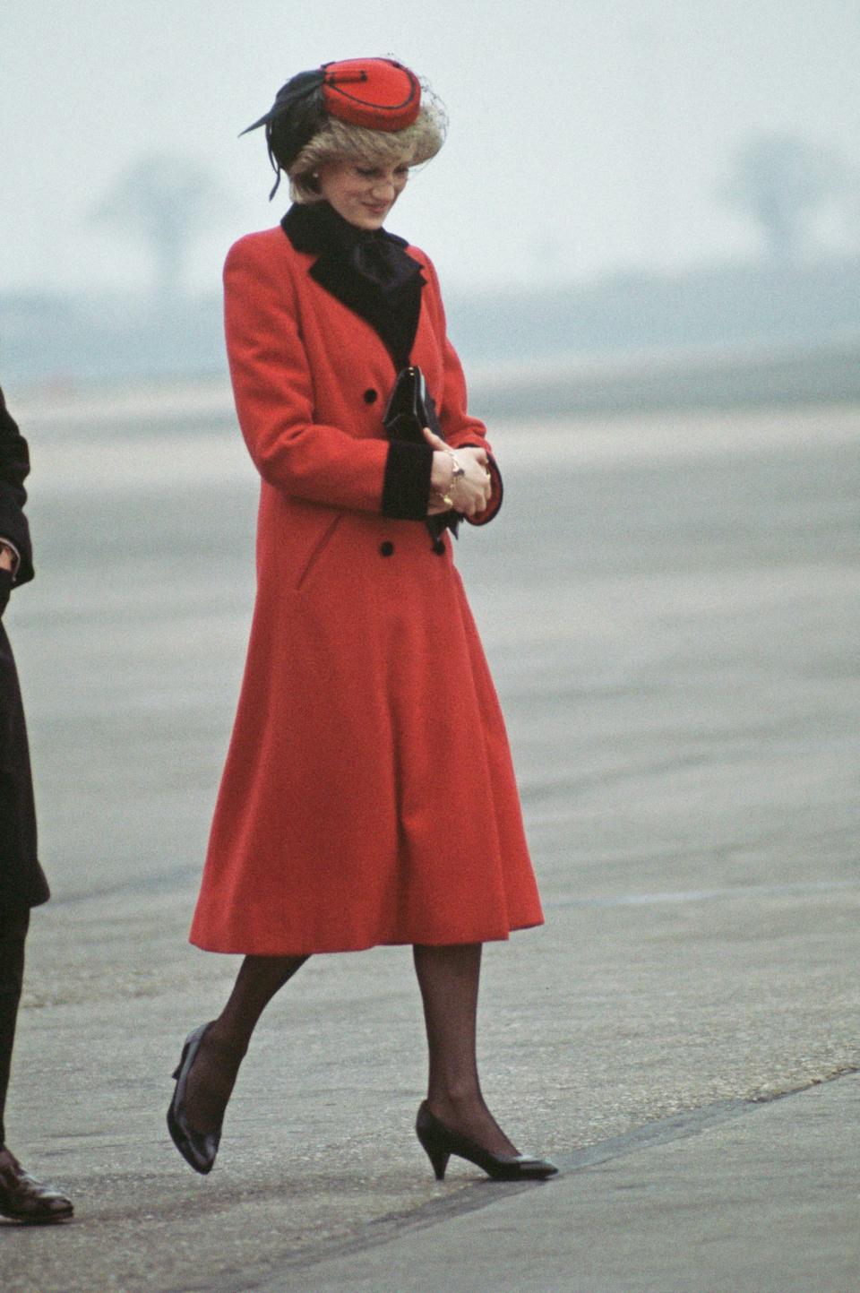 Diana, Princess of Wales wearing a red Catherine Walker coat and a hat by John Boyd upon her arrival at Birmingham airport, England, February 1984.