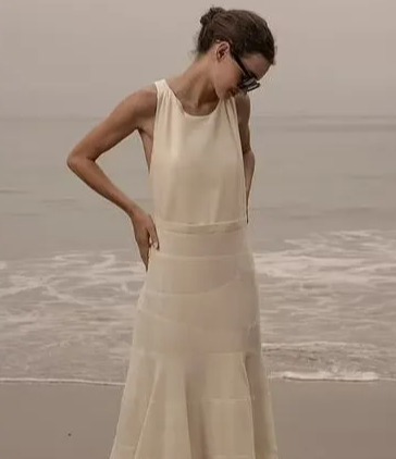 Woman on beach wearing ivory silk gown; product details shown.