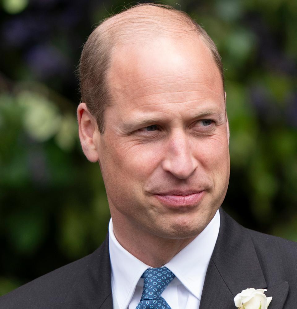  Prince William wearing a suit with a white flower and smiling in front of trees at the Duke of Westminster's 2024 wedding. 