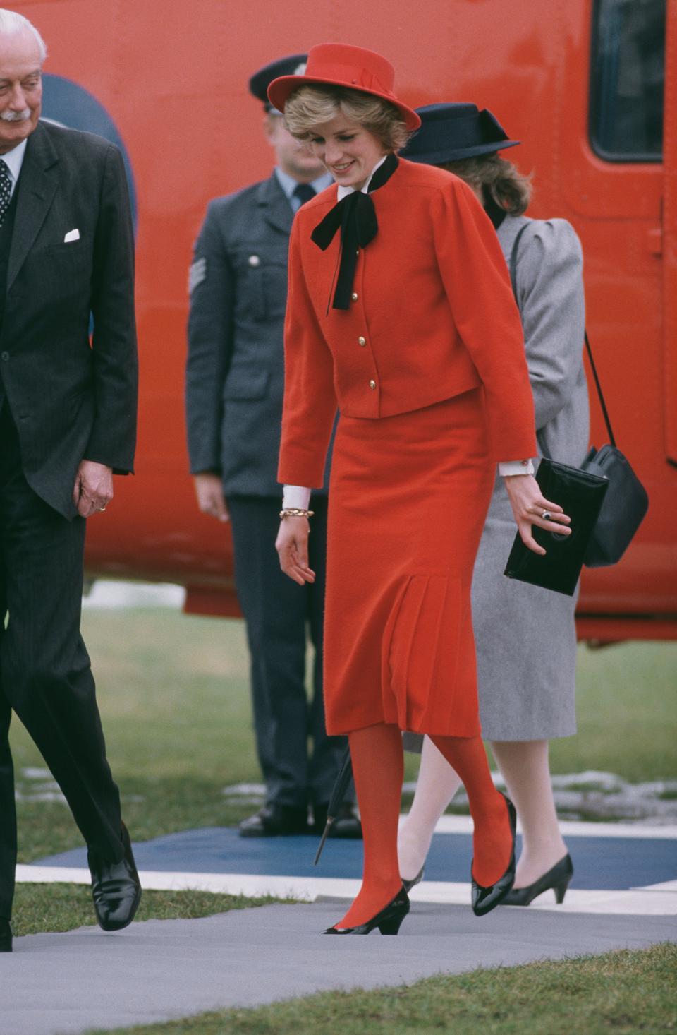 Diana, Princess of Wales arrives in Cirencester, UK, by royal helicopter, February 1985. She is wearing a red suit and matching John Boyd hat.