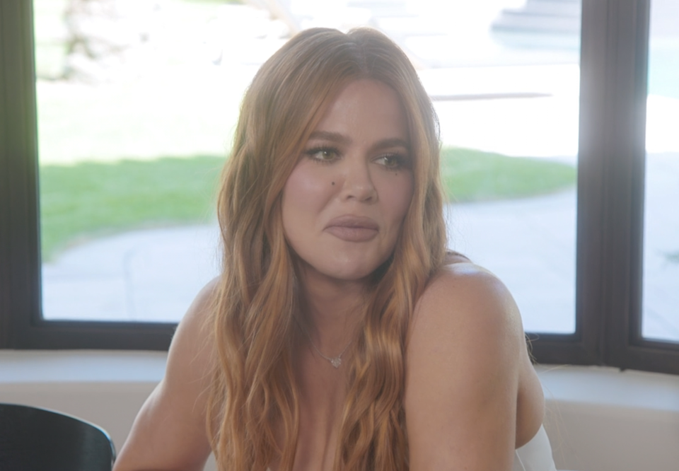 Khloé Kardashian sitting indoors, mid-conversation
