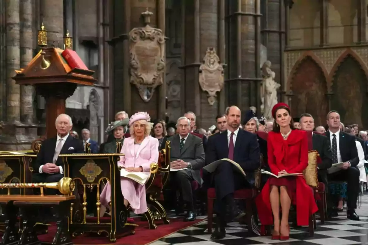 A group of elegantly dressed people is seated at a formal event inside a historic building with detailed architecture. A group of elegantly dressed people is seated at a formal event inside a historic building with detailed architecture.