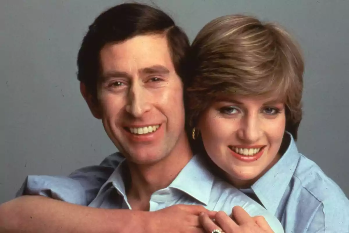 Two people - Lady Di and Charles III - smiling and hugging, both wearing blue jerseys.