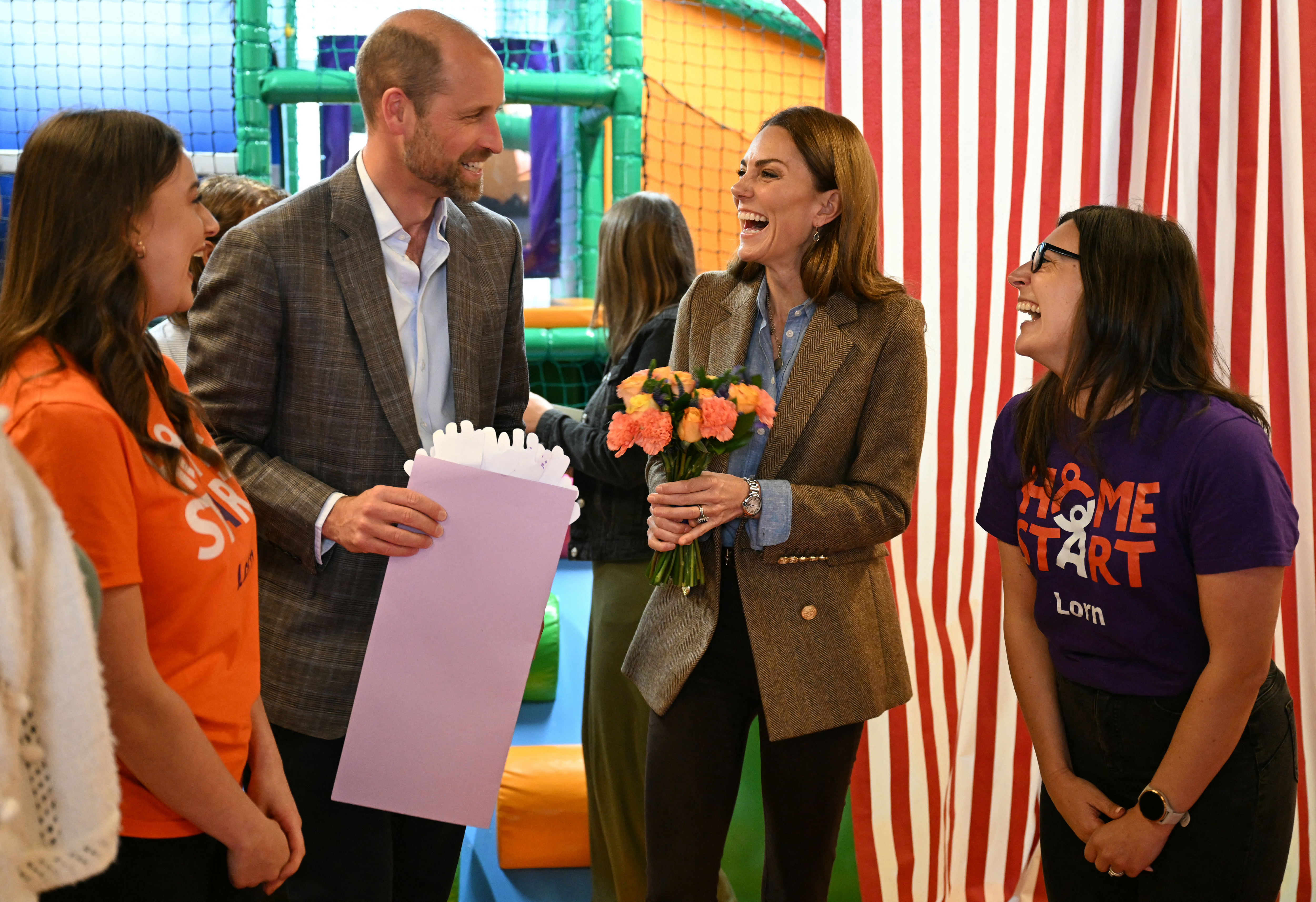 Prince William and Catherine, Princess of Wales, laughing during a visit to a soft play area.