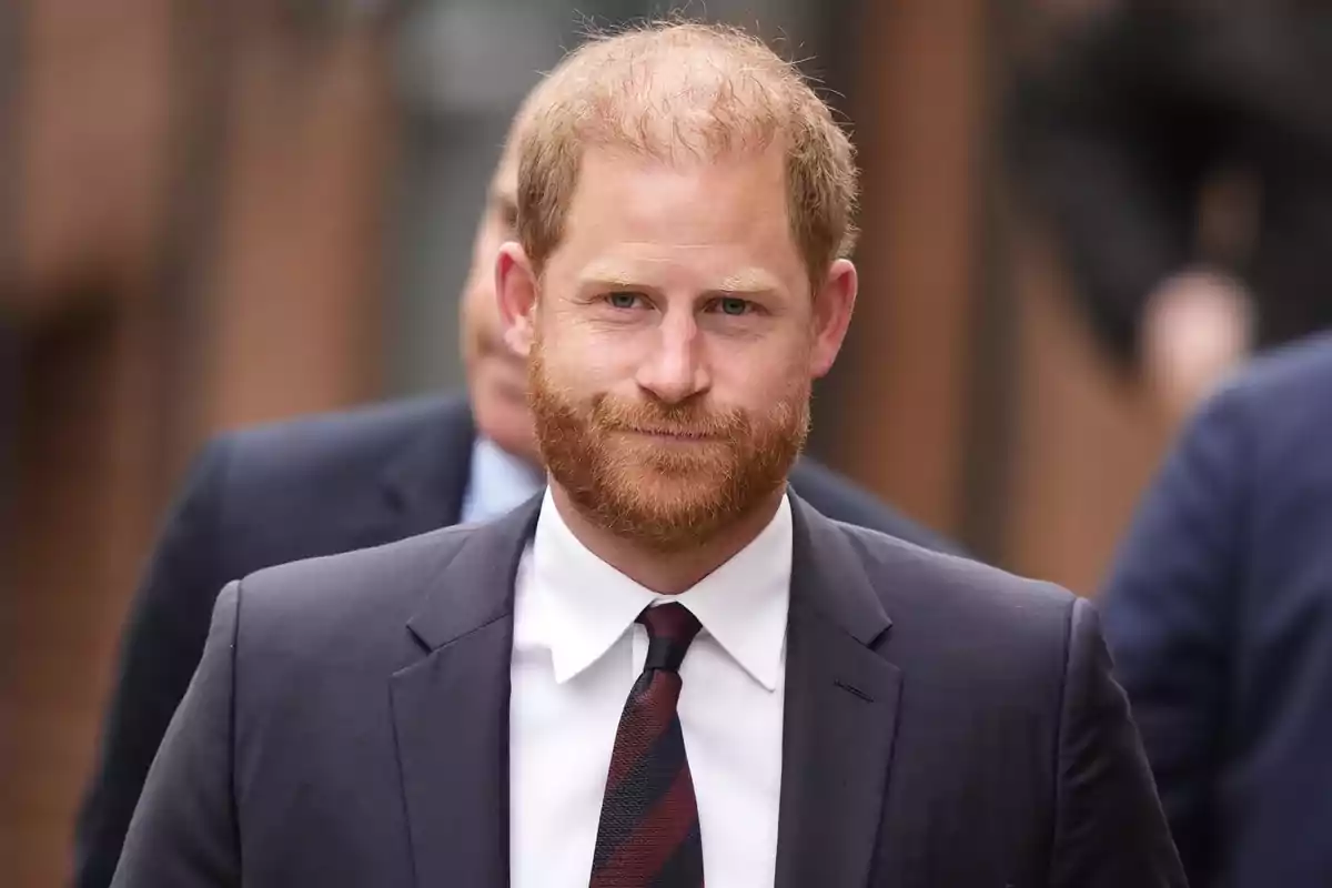 Prince Harry in a dark suit walks outdoors. Prince Harry in a dark suit walks outdoors.
