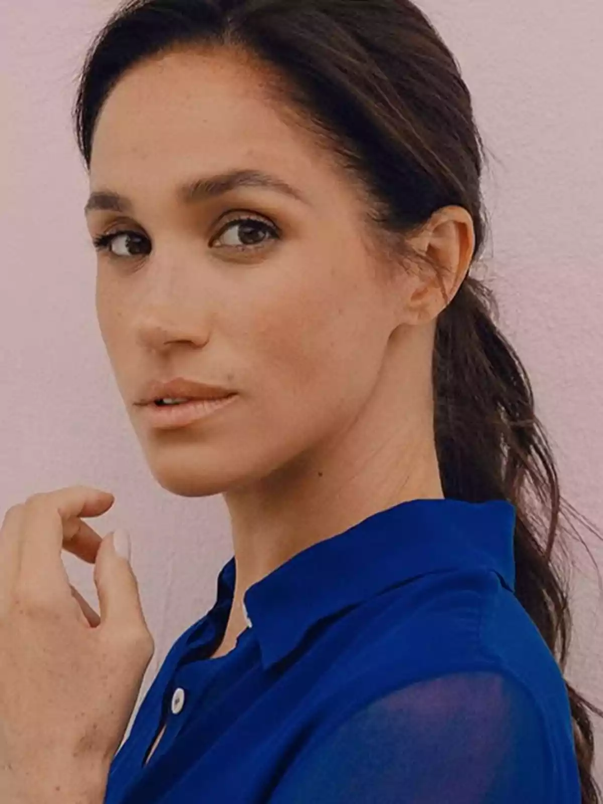 Meghan Markle, wearing a blue blouse, looking at the camera with a thoughtful expression. Meghan Markle, wearing a blue blouse, looking at the camera with a thoughtful expression.