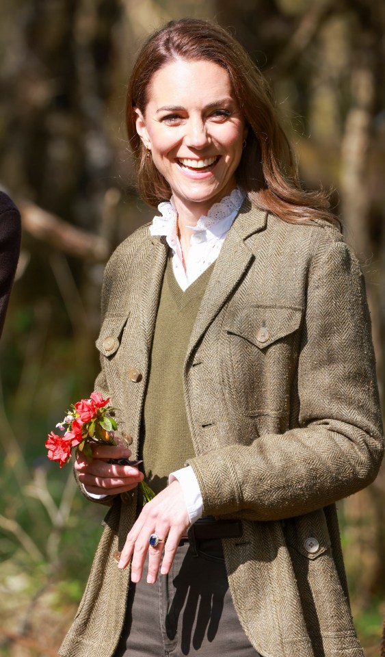 Catherine, Princess of Wales, smiling and holding flowers.