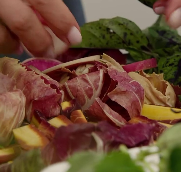 Close-up of hands preparing radicchio and other vegetables.