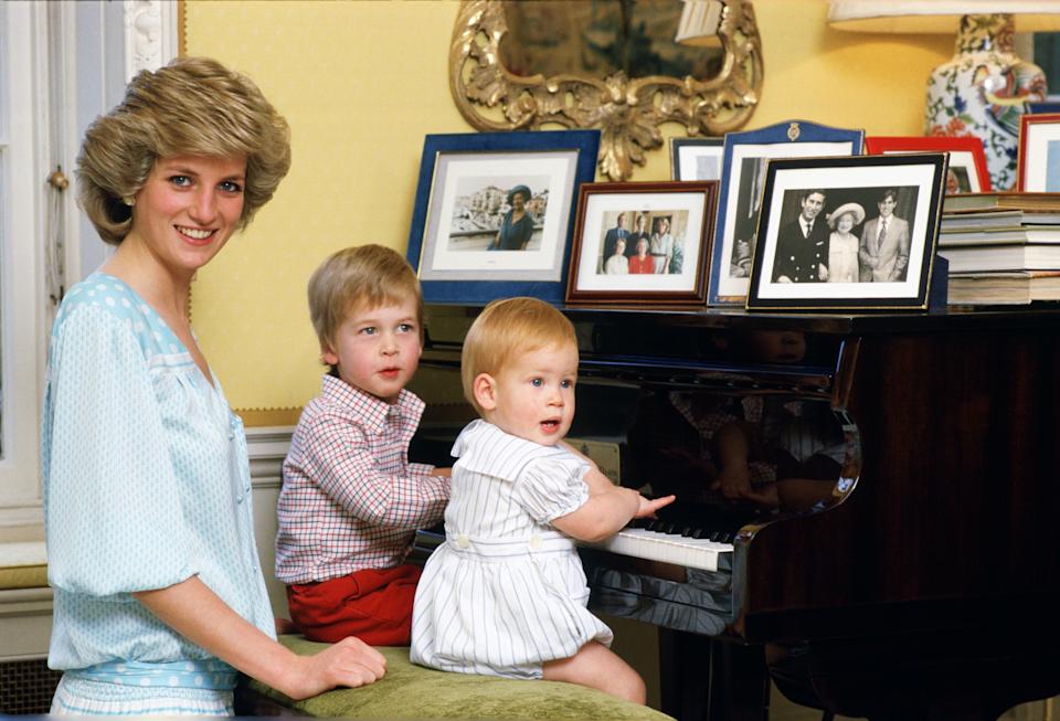 Princess Diana sitting at a piano with baby Prince Harry and Prince William