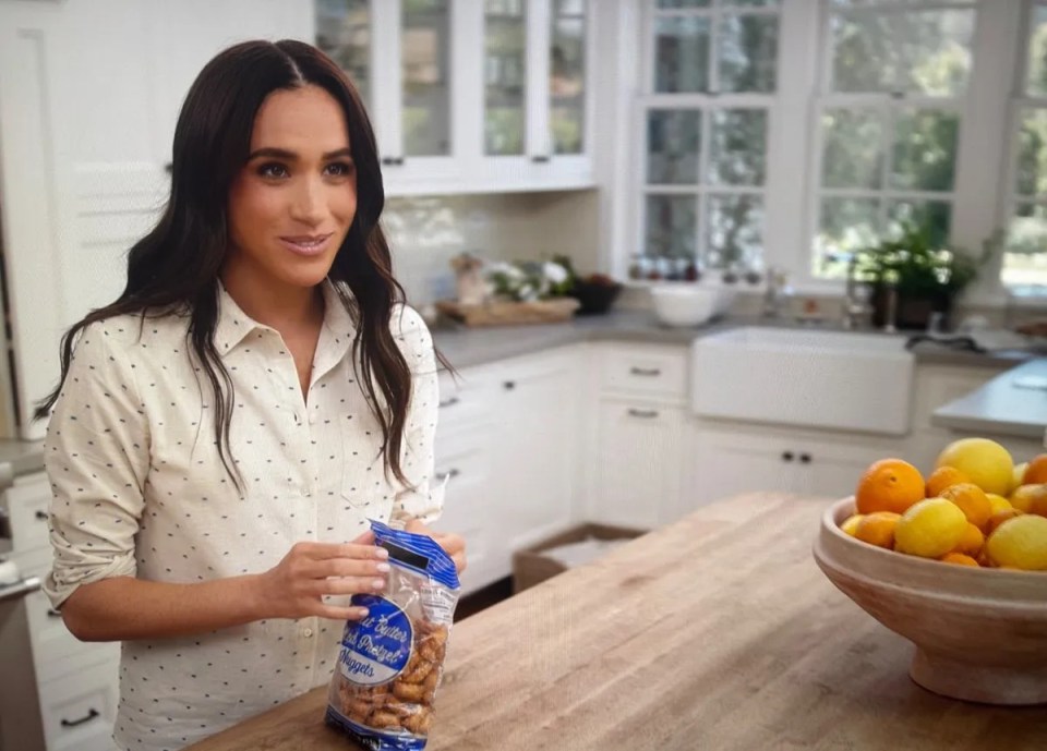 Meghan Markle holding a bag of pretzels in a kitchen.
