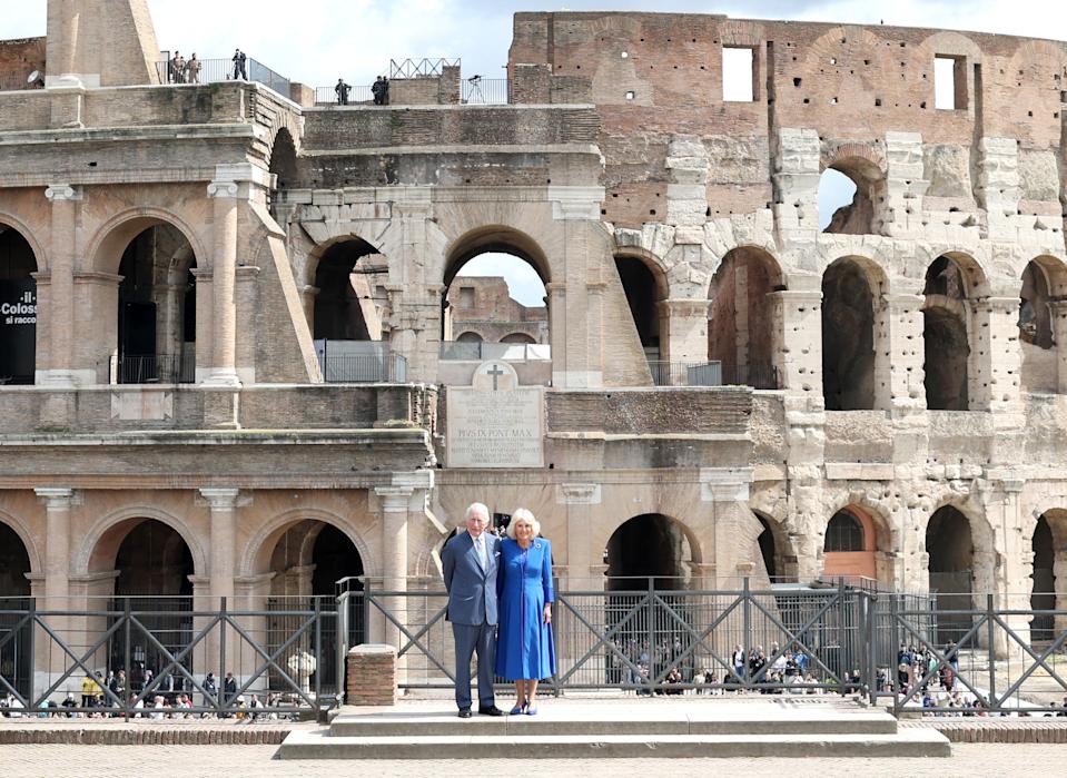 Queen Camilla wearing a blue coat and King Charles wearing a suit standing in front of the Colosseum on April 8, 2025