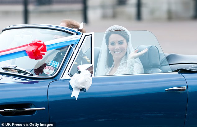 A smiling Duchess of Cambridge being driven out by Prince William in an Aston Martin