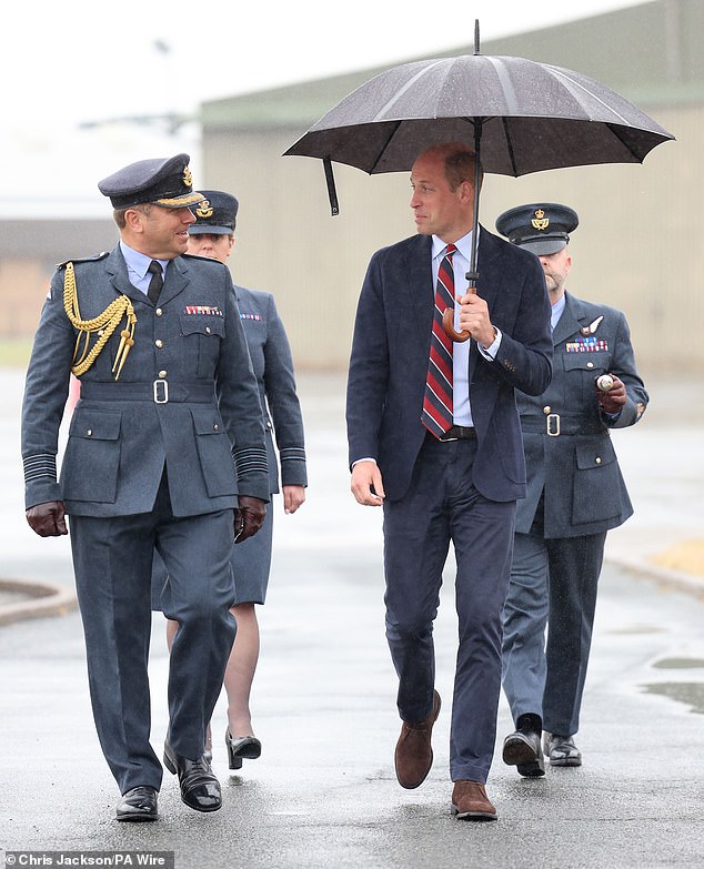 William, 42, beamed despite the glum weather as he sheltered himself with an umbrella. The royal donned a navy suit, teamed with a white button-down and a red and black tie, for the occasion