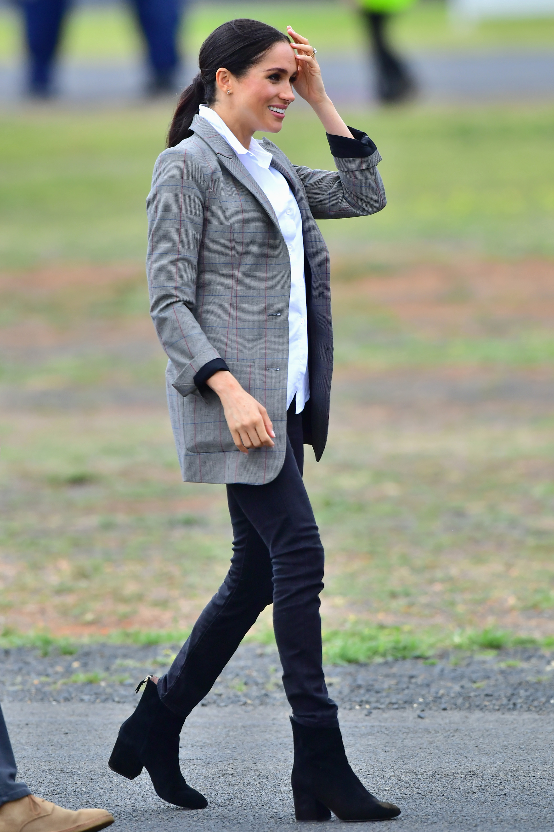 Meghan Markle wearing black jeans and a gray blazer walking outside in Australia