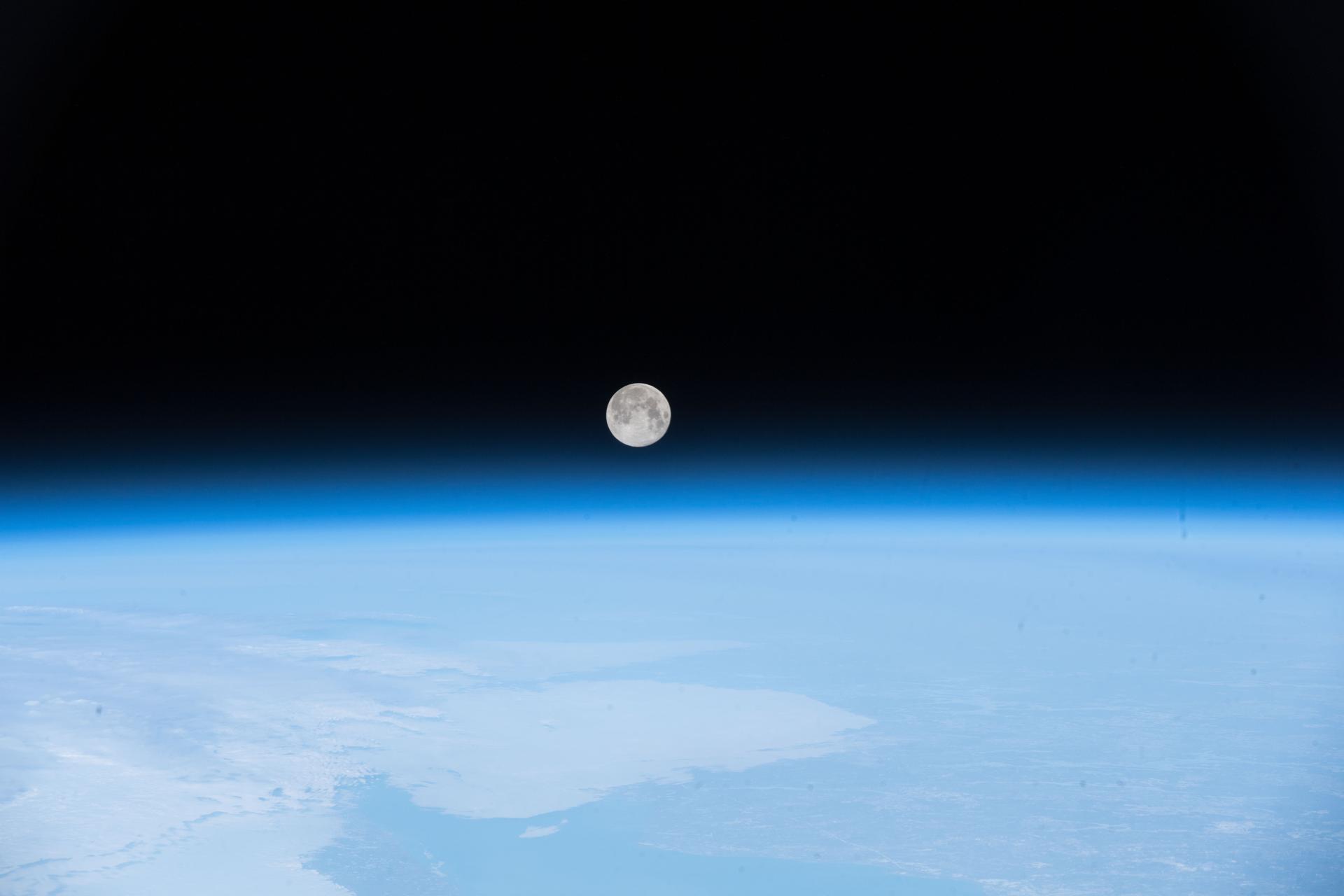 A pink moon hangs in the sky above Earth