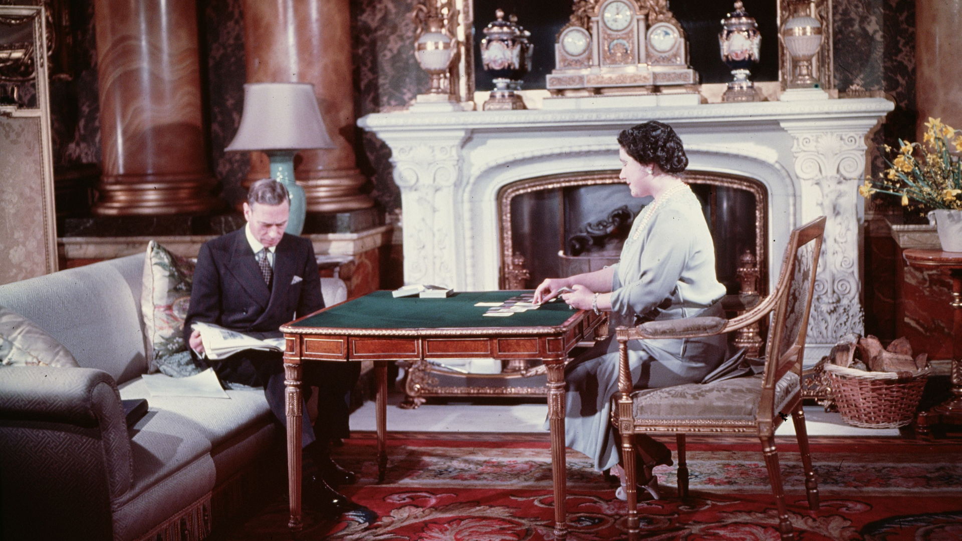 King George VI (1895 - 1952) and Queen Elizabeth (1900 - 2002) entertain themselves during a quiet moment at Buckingham Palace, London in 1942