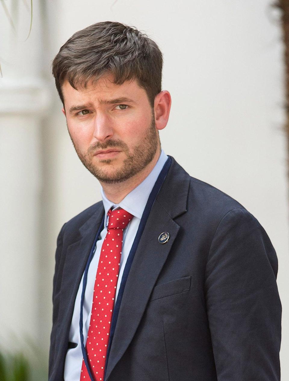 Jason Knauf wearing a dark suit and a red tie.