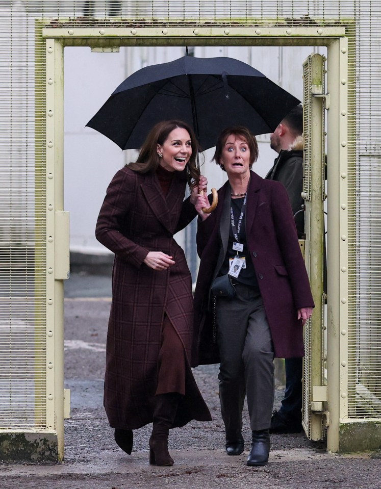 Princess Catherine and a prison worker under an umbrella.