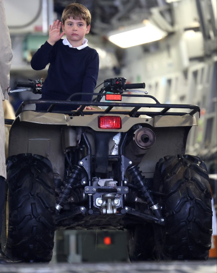 Prince Louis of Wales waving from a quad bike inside a plane.