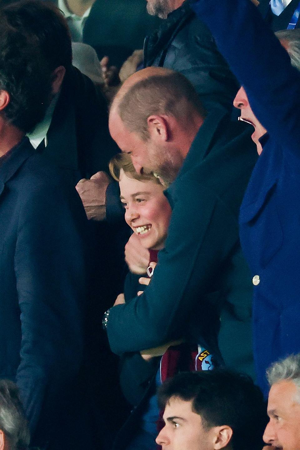 Prince William laughing and holding onto a smiling Prince George