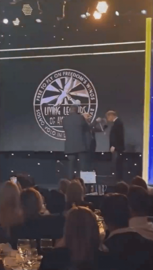 Award ceremony: two people on stage receiving an award.