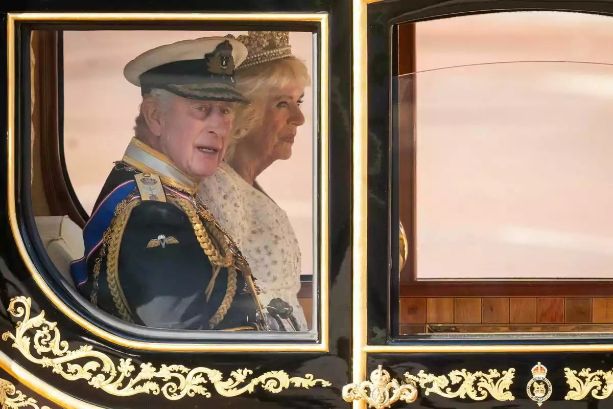 A couple dressed formally travels in a carriage decorated with golden details. A couple dressed formally travels in a carriage decorated with golden details.