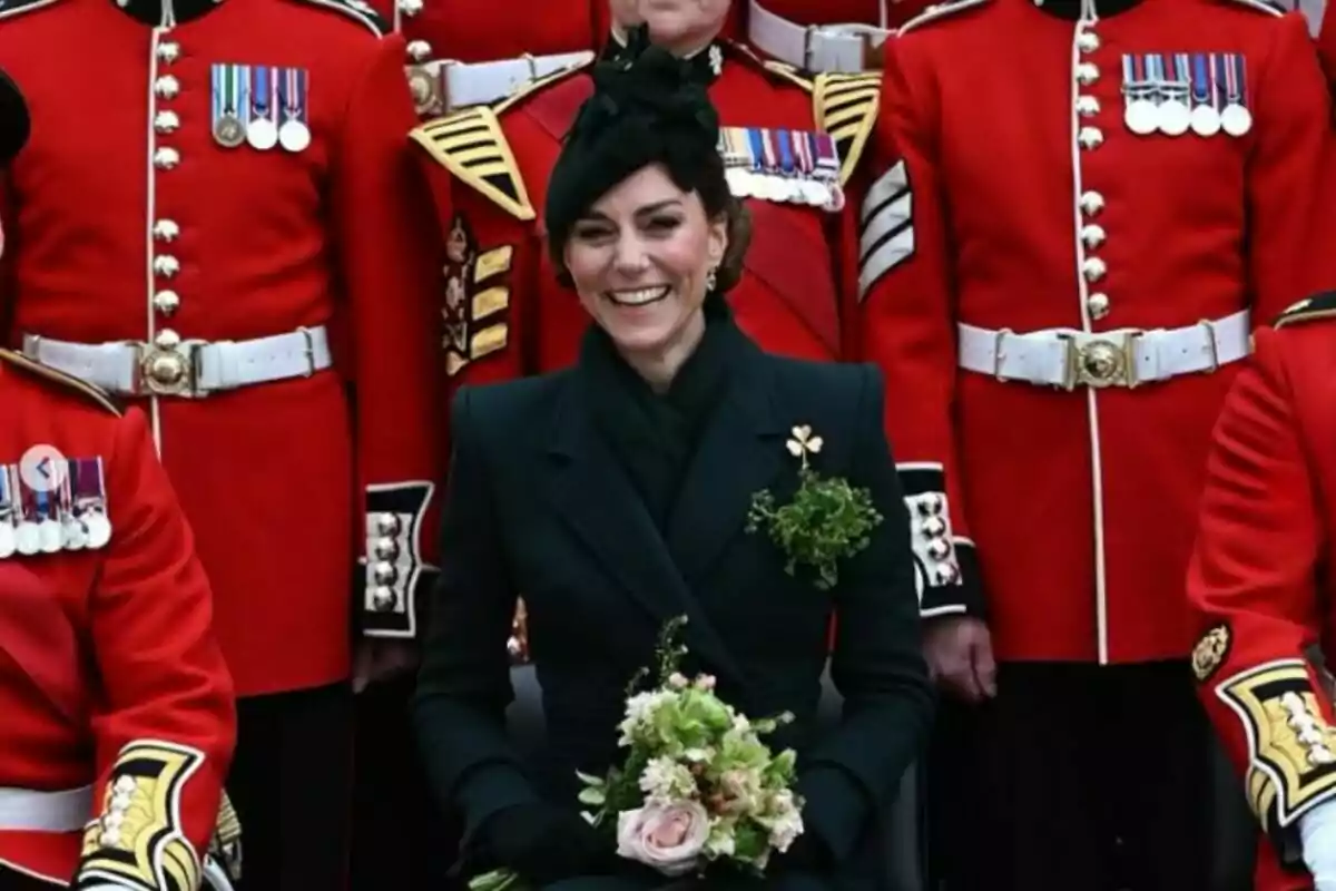 A smiling woman dressed in black with a bouquet of flowers in her hands, surrounded by people in red uniforms decorated with medals. A smiling woman dressed in black with a bouquet of flowers in her hands, surrounded by people in red uniforms decorated with medals.