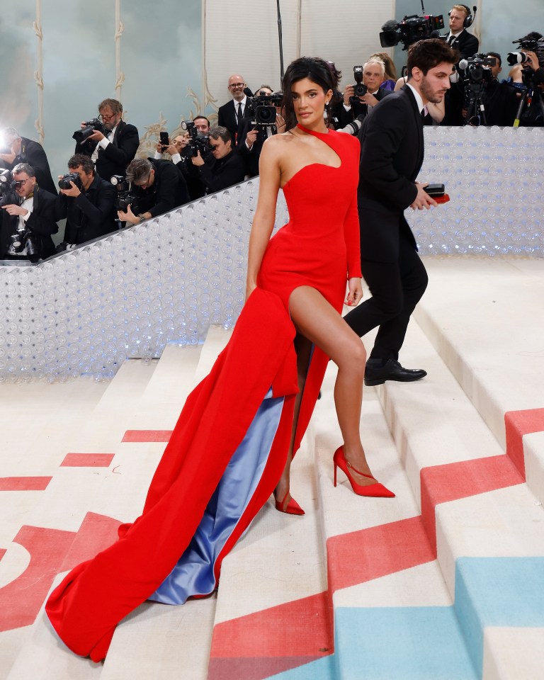 Kylie Jenner in a red dress on the Met Gala stairs.