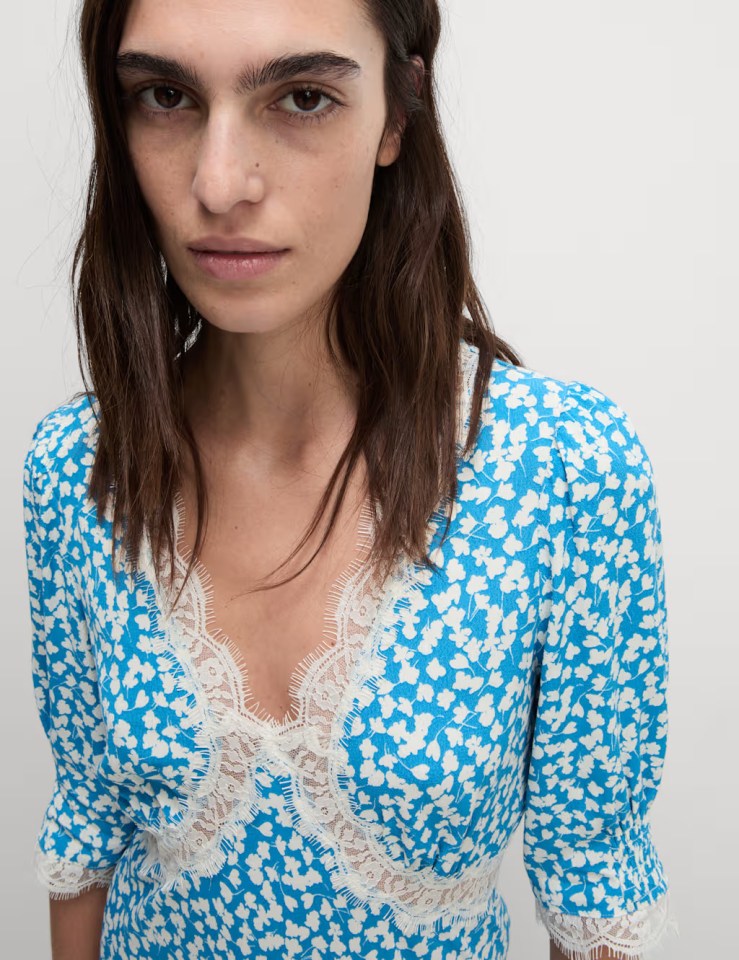 Woman wearing a blue floral dress with lace trim.