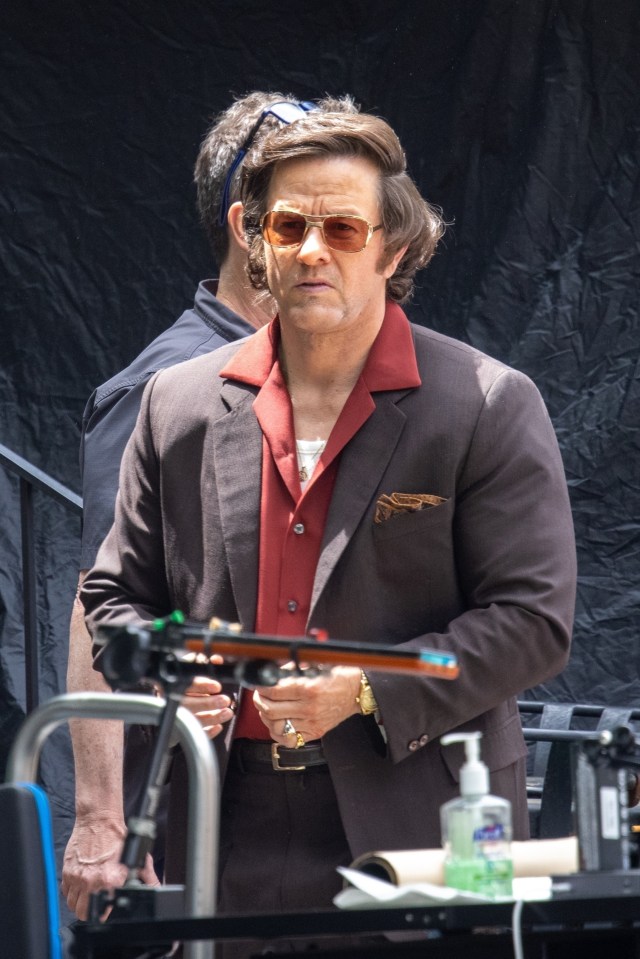 Mark Wahlberg on the set of "By Any Means," wearing a brown suit and sunglasses.