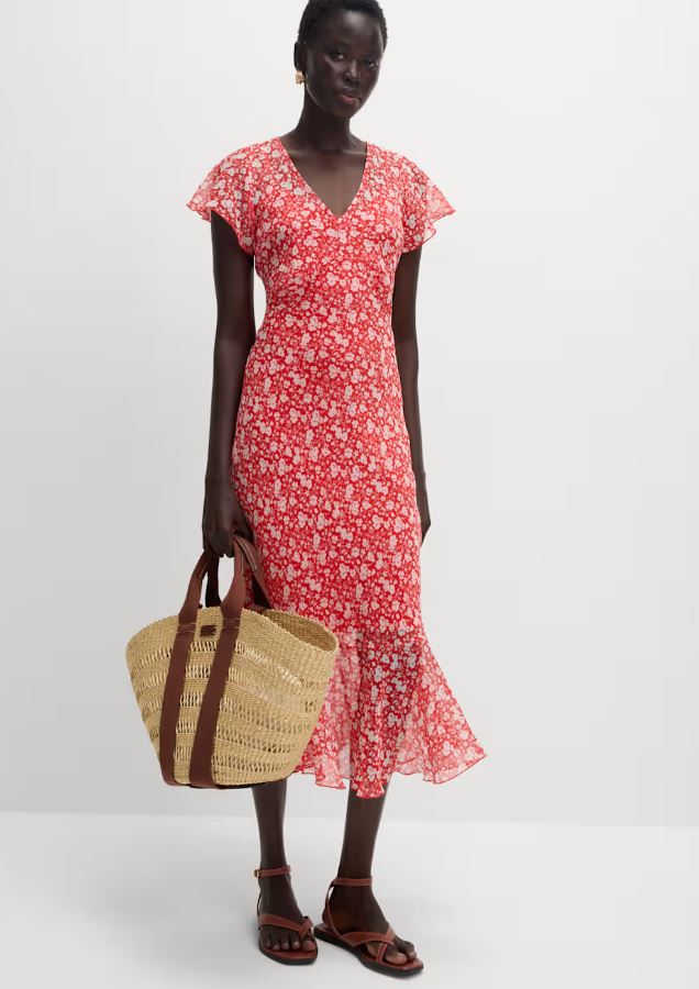 Woman in red floral midi dress and sandals, carrying a straw tote bag.