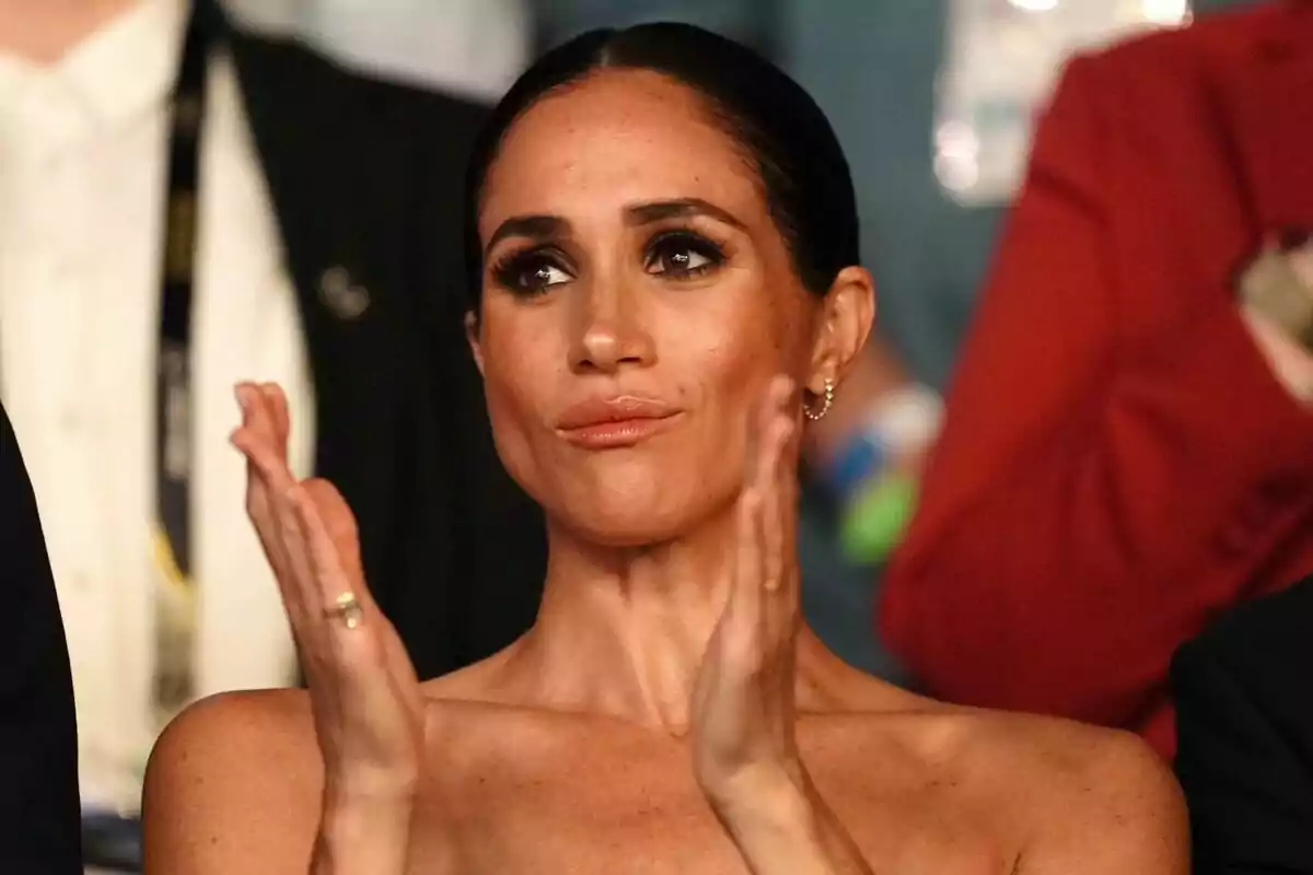 Meghan Markle clapping with a serious expression at an event.