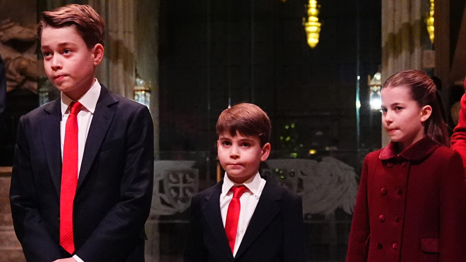 Prince George and Prince Louis wear matching suits with white shirt and red ties, while Princess Charlotte wears a red coat to attend Kate Middleton's Christmas carol concert