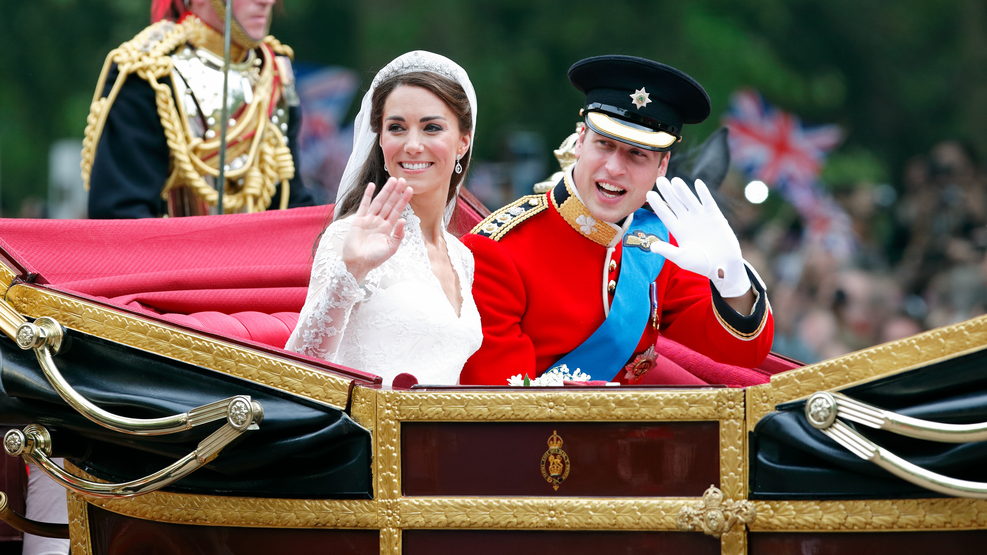 Catherine, Princess of Wales and Prince William wave as they travel by horse drawn carriage following their wedding ceremony at Westminster Abbey on April 29, 2011