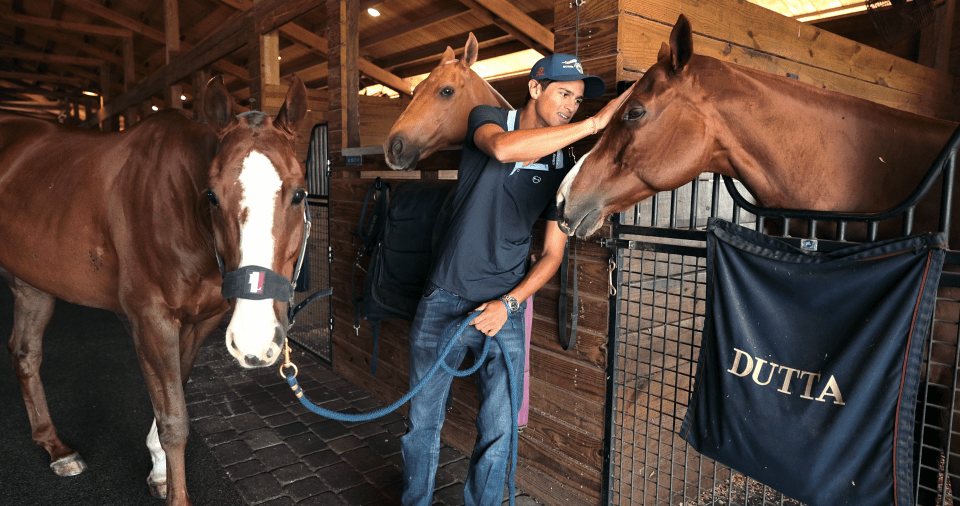 Timmy Dutta with polo ponies in a stable.