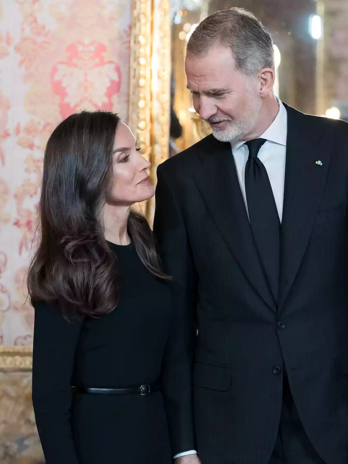 Queen Letizia smiling next to Felipe VI looking at her.