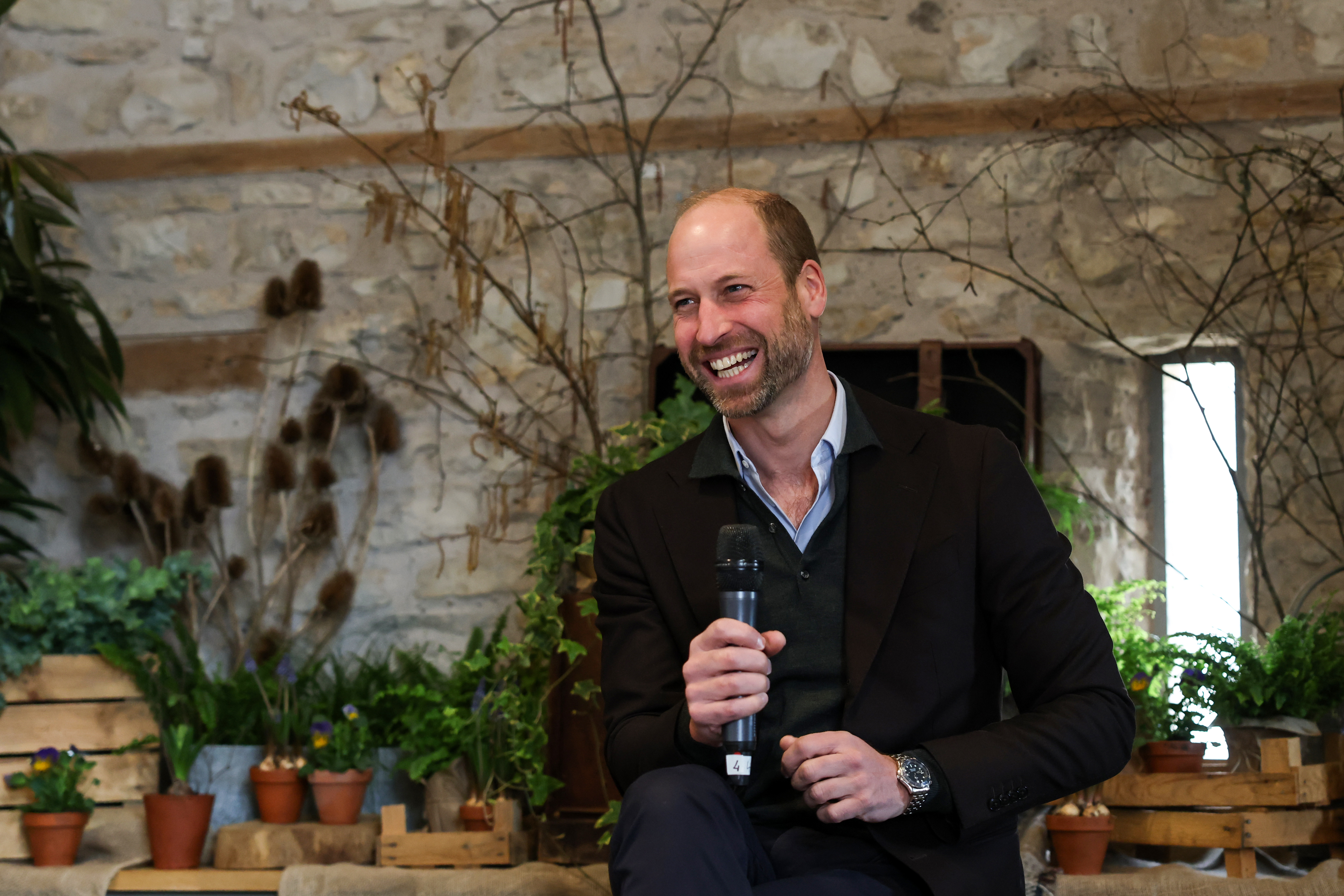Prince William speaking into a microphone with plants in the background