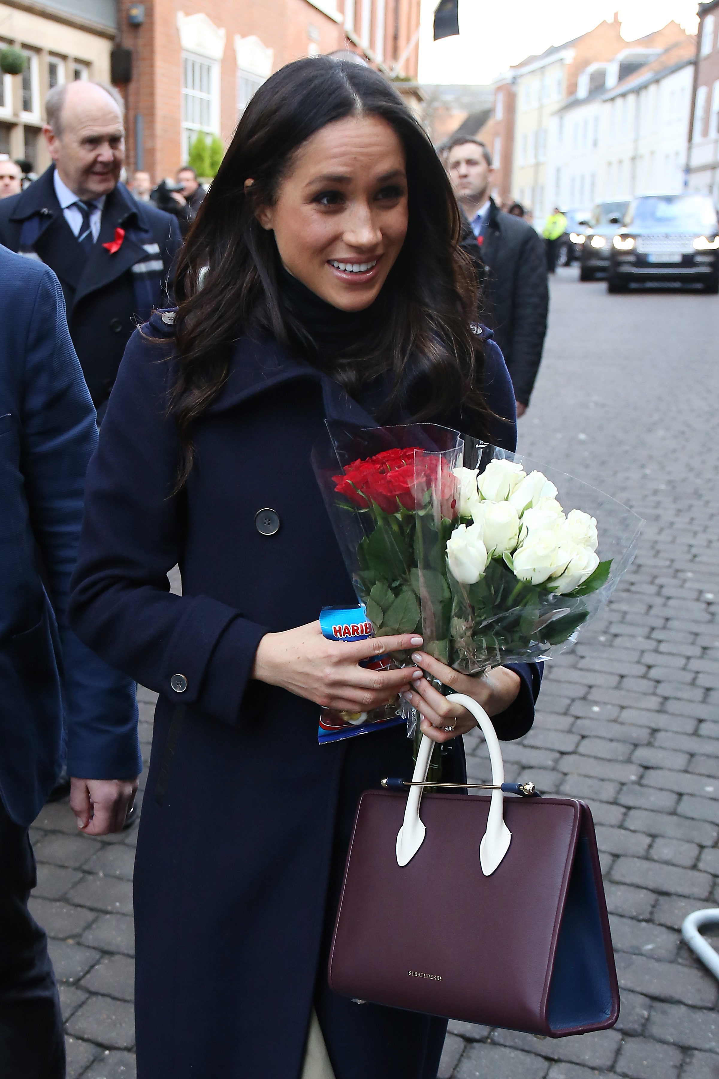 Meghan Markle carrying a Strathberry tote and flowers in 2017