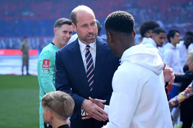 rince William, Prince of Wales shakes hands with Marc Guehi of Crystal Palace
