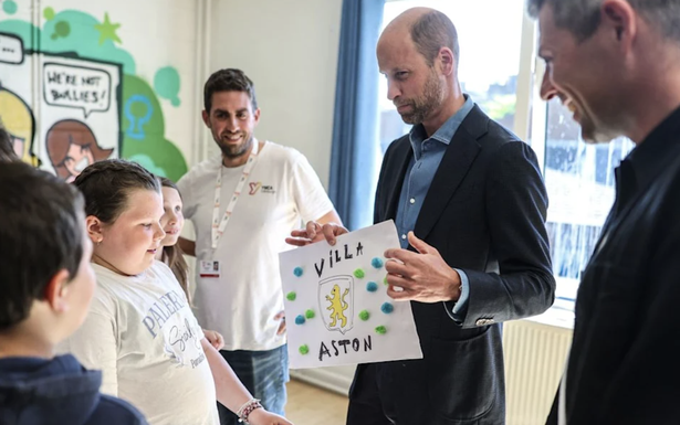 Prince William holding up a hand drawn poster of his favourite football team - Aston Villa 