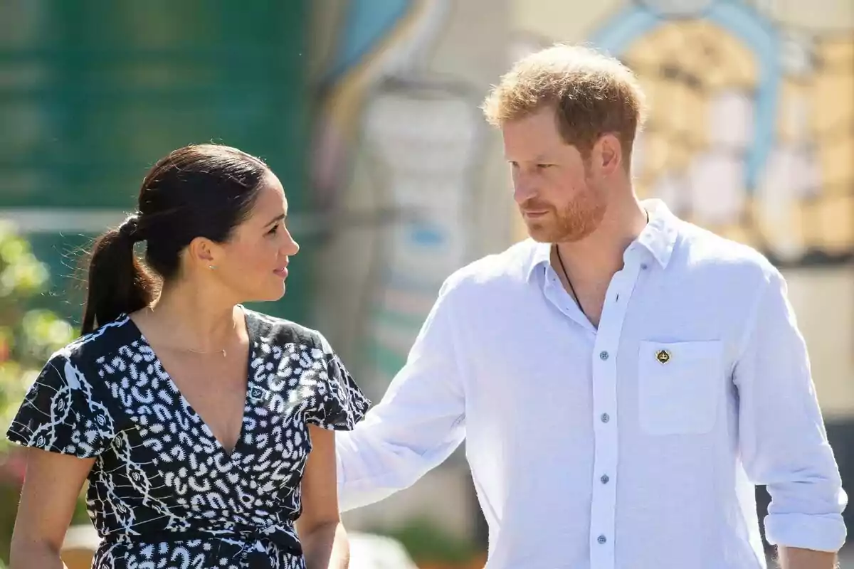 A couple walking outdoors while looking at each other affectionately.