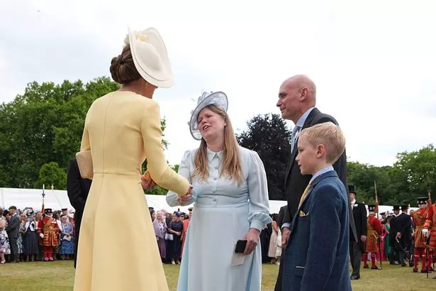 Kate talks to guests as she wears an Emilia Wickstead dress and Philip Treacy hat 
