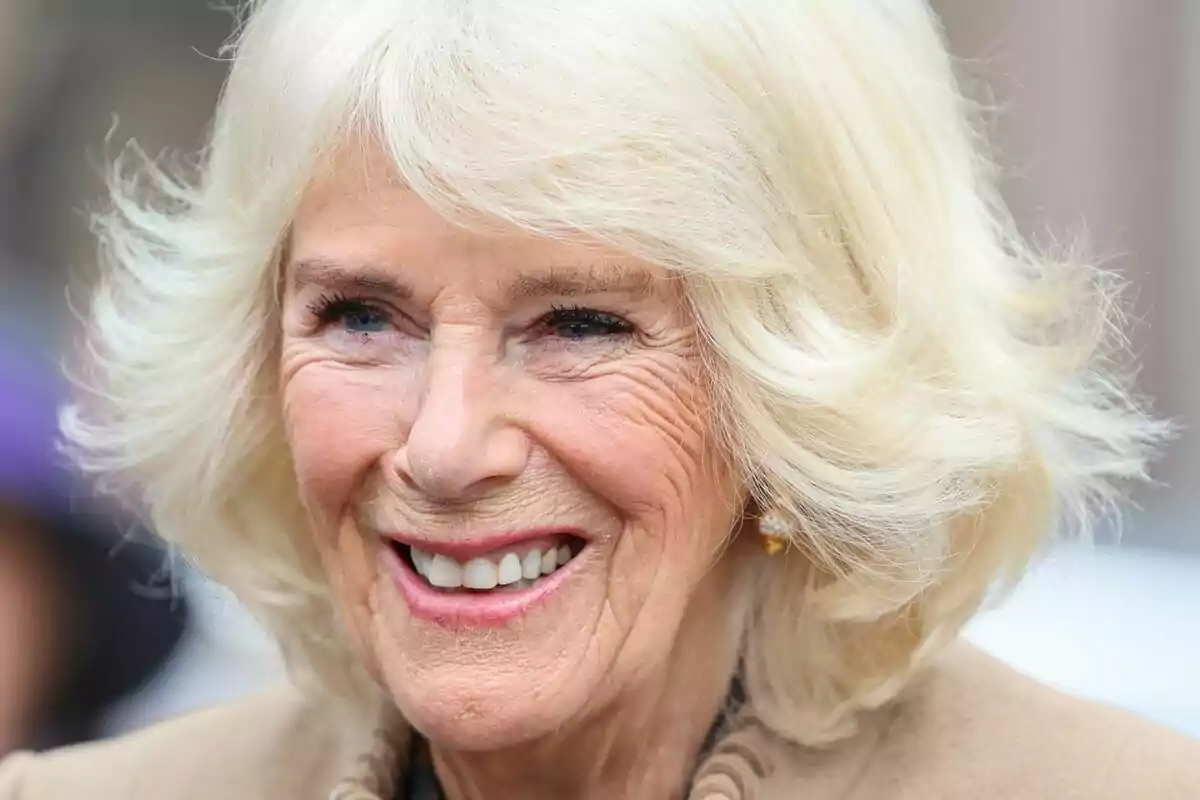 An elderly person with blonde hair and a wide smile.