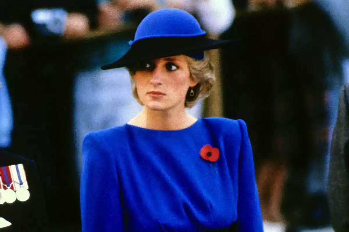 A person with an elegant blue hat and matching dress wears a red poppy brooch.