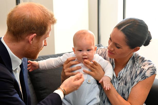 Photo of the Duke and Duchess of Sussex smiling at each other while the Duchess holds their newborn son Prince Archie. They are posing for photos during a promotional trip to South Africa.